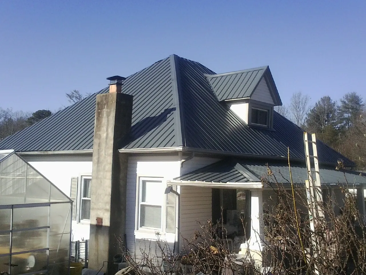 Dark blue standing seam metal roof on a white farmhouse with dormer — Slate & Tile Roof Repair by Roofing Brothers in Troy